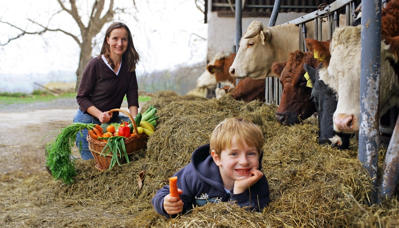 Das Bild zeigt eine Mutter mit ihrem Kind auf einem Bauernhof